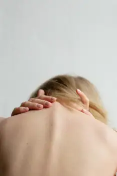 Mulher com dor na região da nuca causada por tensão muscular